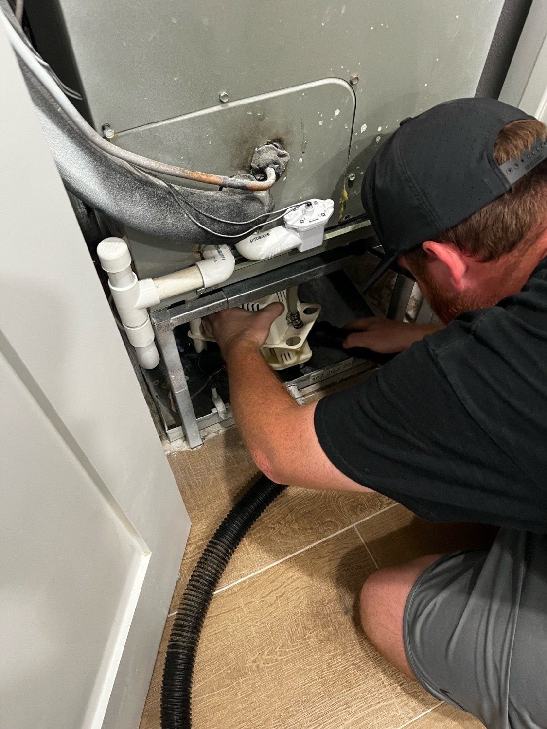 Always Be Cooling technician clearing an AC drain line at a Naples FL home